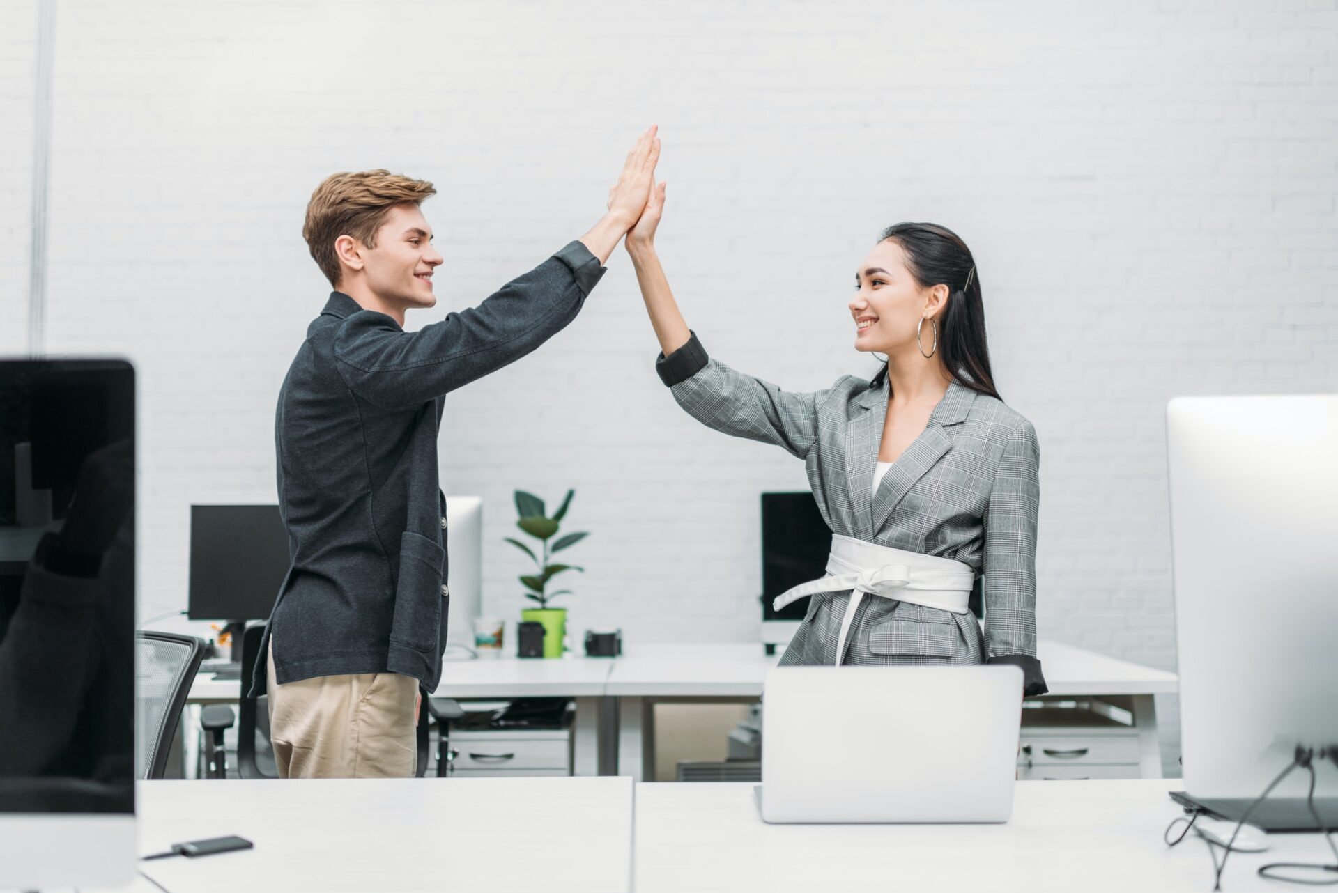 multiethnic business partners giving high five at office